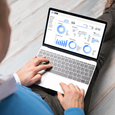 A professional woman smiling while using a CRM on her laptop.